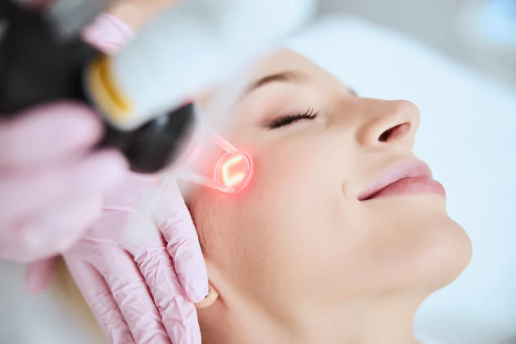 Practitioner performing a facial treatment with a handheld device on a client