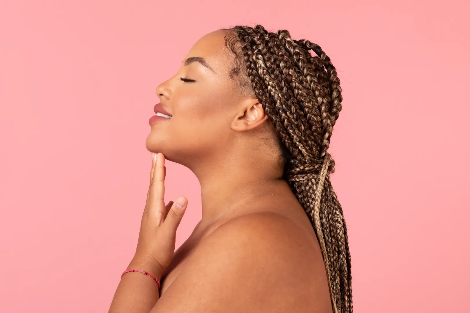 Side profile of a woman with braided hair gently touching the area beneath her chin.